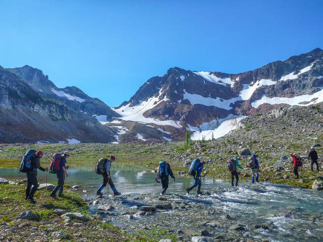 Naval Academy Mountaineering course participants cross a stream while backpacking.