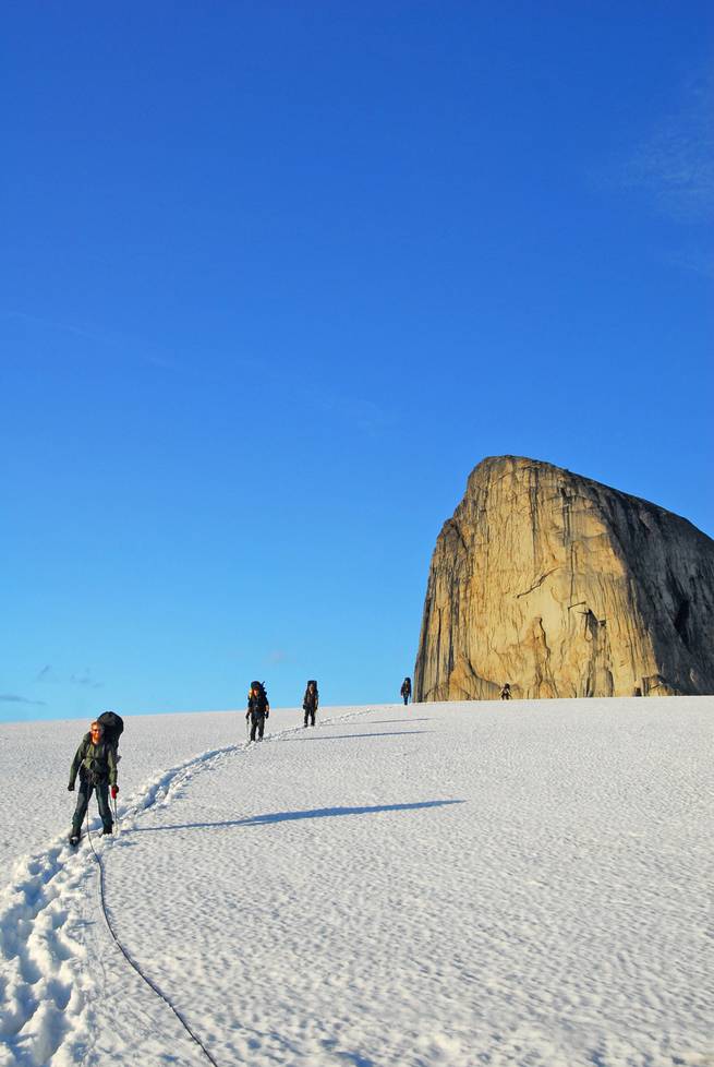 Students hike down a snowy slope while mountaineering in the Yukon.