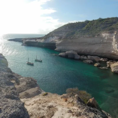 Sailboats anchored in a protected cove at sunset.