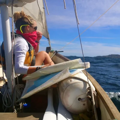 A student with a handkerchief covering face using a map to navigate the sea.