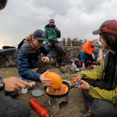 Students gathered around a camp stove, preparing a meal while on a course in India.