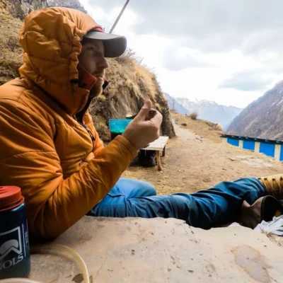 Student resting against a rock, while eating a meal in India.