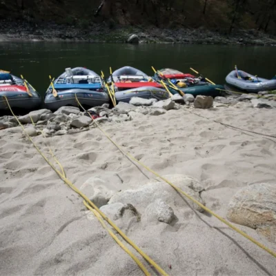 Five rafts are tied up for the evening on a sandy shore in Idaho.