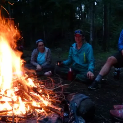 Students and instructors sitting around a campfire in the evening.