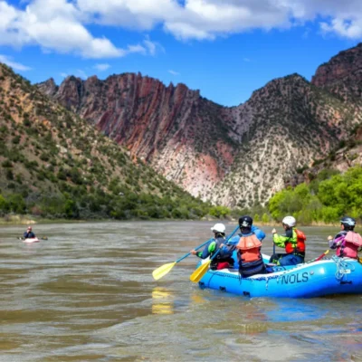 Course participants paddle in a raft and on kayaks on the riverCourse participants paddle in a raft and on kayaks on the river.
