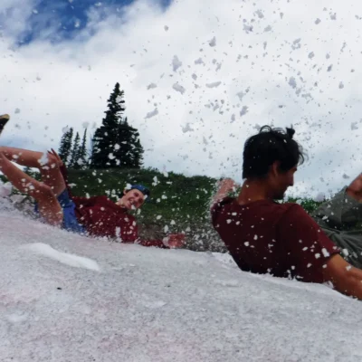 Students slide down an old snow bank.