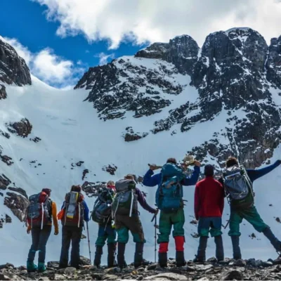 A group of students pauses while backpacking in Patagonia to enjoy the rugged snowy mountains around them.