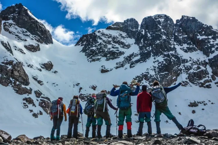 A group of students pauses while backpacking in Patagonia to enjoy the rugged snowy mountains around them.