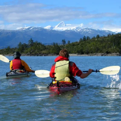 Students sea kayaking through Patagonia gaze at snow capped mountains in the distance.