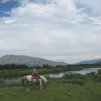 A horse and rider pause to enjoy the view by a Wyoming river.