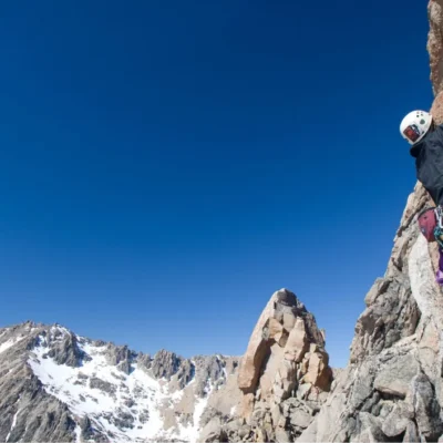 A student rock climbs near snow-dusted peaks in Patagonia.