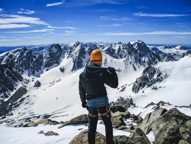 A student holding an ice ax gazing across the vast Wind River range.