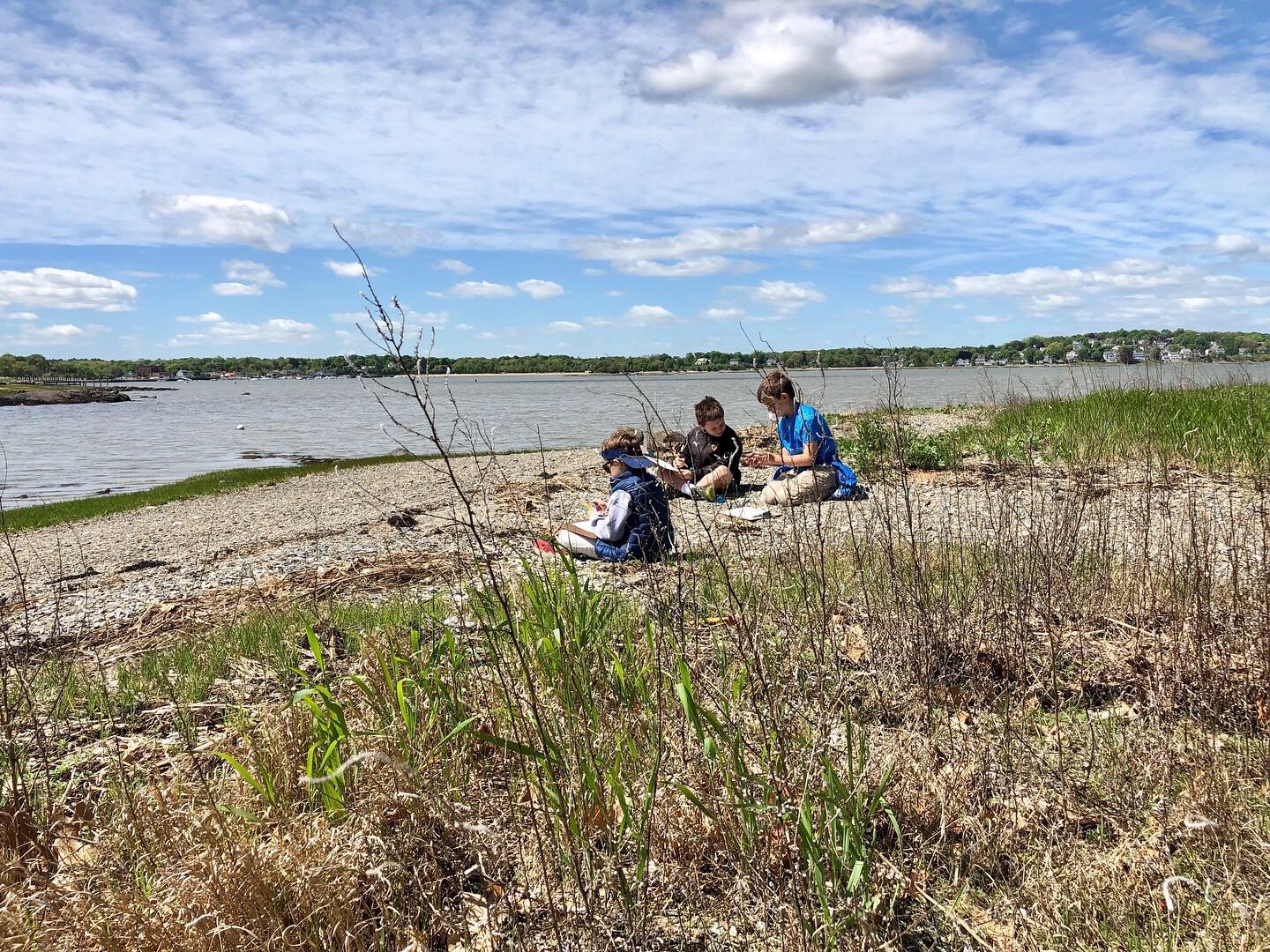 School-age children sit on a shore and do art projects
