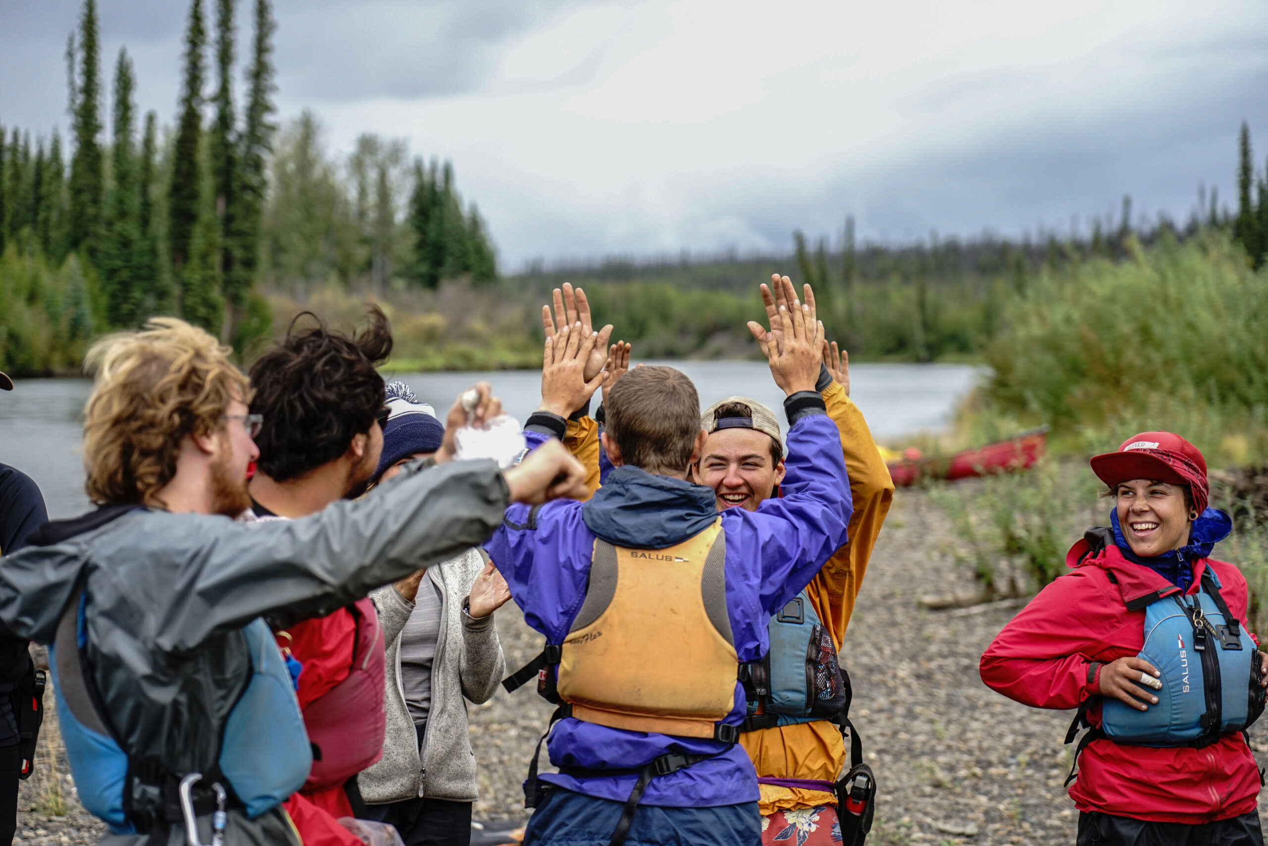 Students high five on the bank of a river