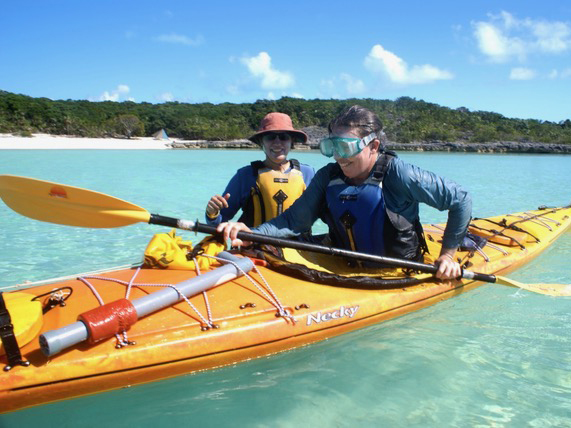 NOLS Alumni student in a kayak wearing goggles with an instructor standing by her.