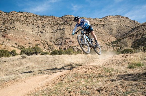 mountain biker with both tires off the ground on dirt trail