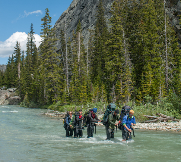 five NOLS participants cross river in Wyoming's Wind River Range