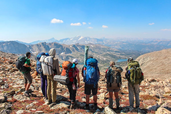seven NOLS participants backpacking in Wyoming's Wind River Range look out at a view of lakes and mountains
