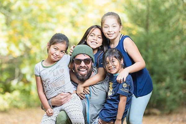 Jorge Moreno surrounded by four smiling children while volunteering at Latino Outdoors