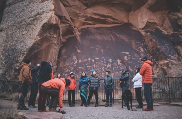 Messengers Run group in front of rock face with petroglyphs
