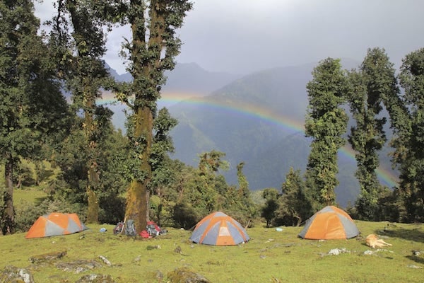 several tents set up in India's Pindari range with rainbow in background on NOLS backpacking course