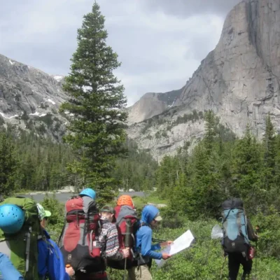 Many students backpacking to the base of a climbing wall in the Wind River Wilderness.