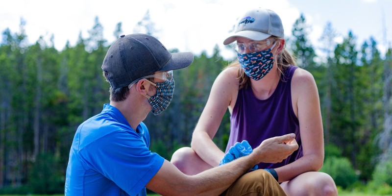 Woman in a mask checks a man's pulse
