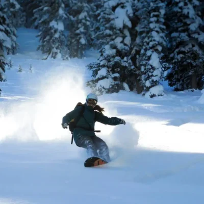 Student coasts across the backcountry powder on a backcountry splitboarding course.