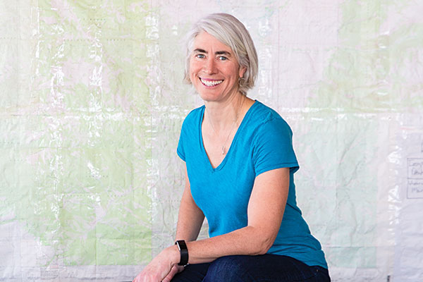 Portrait of Abby Warner, director of NOLS Teton Valley, with map in background