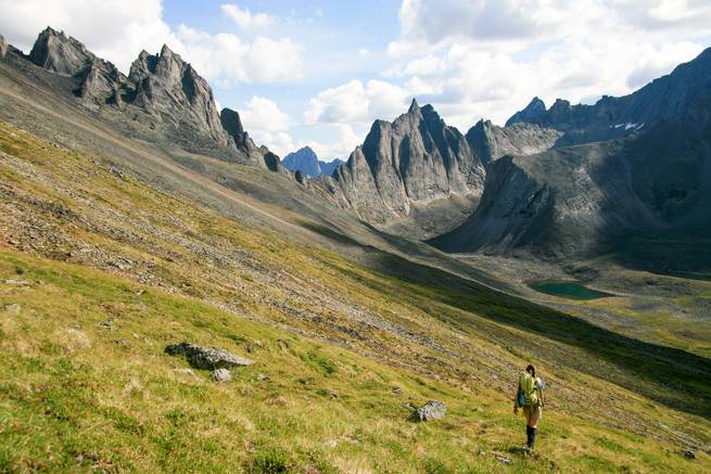 A student hikes into a sweeping valley ringed with jagged peaks while backpacking in the Yukon.