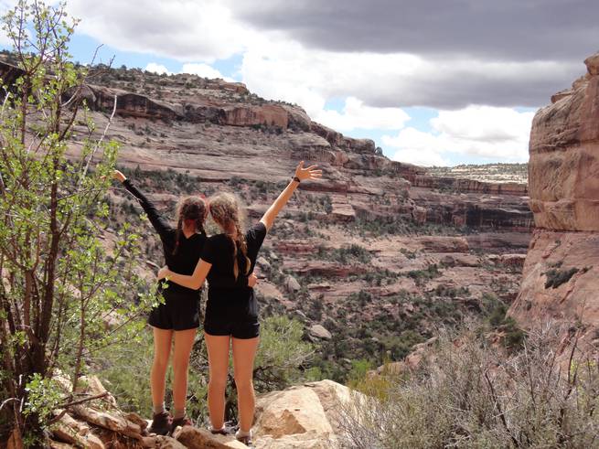 Students on an Archer 7th Grade Girls Expedition throw up their arms while looking out into the canyons of Utah's Cedar Mesa area.