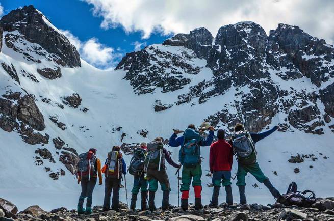 A group of students pauses while backpacking in Patagonia to enjoy the rugged snowy mountains around them.
