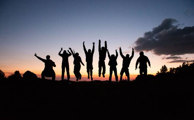 Students jump into the sunset after a long day hiking.