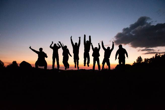 Students jump into the sunset after a long day hiking.