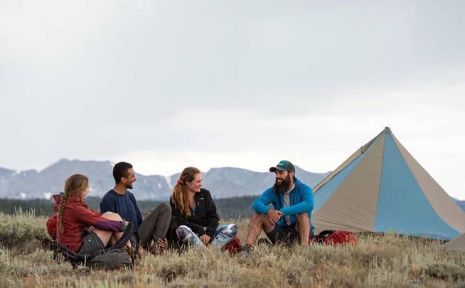 Four students chatting together outside a tent in camp.