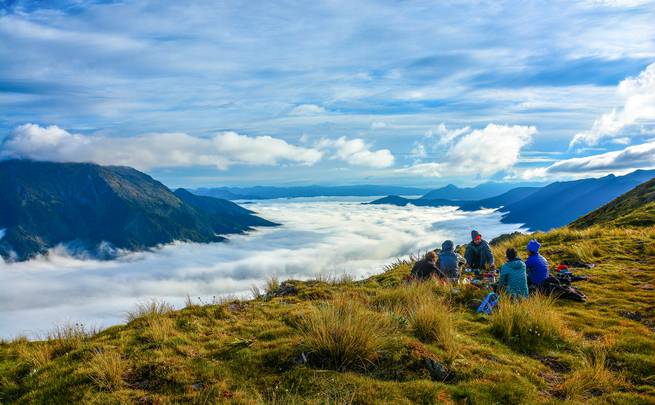 Course participants sit on a grassy ridge above the clouds in Kahurangi National Park.