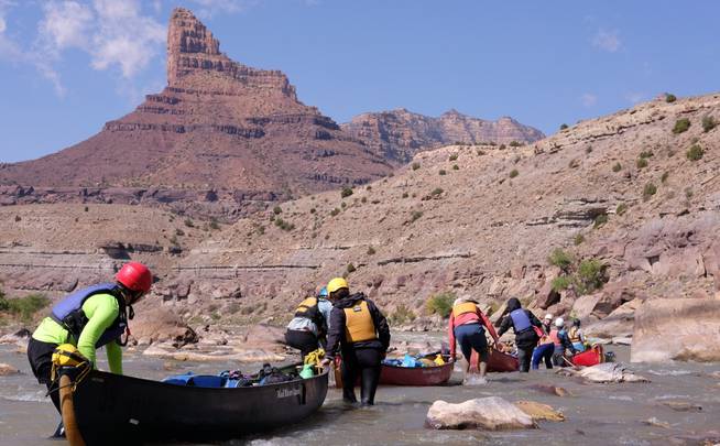 A group of students navigates canoes through a rapid