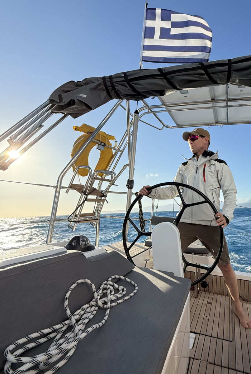 A member of the crew steering the sailboat on open water.