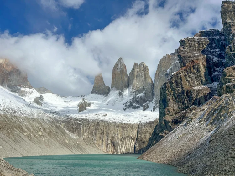 steep peaks with snow at their base drop into turquoise water.