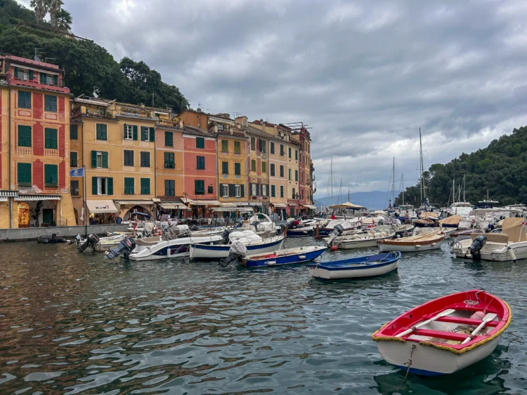 Boats are anchored in the marina with colorful buildings in the background.