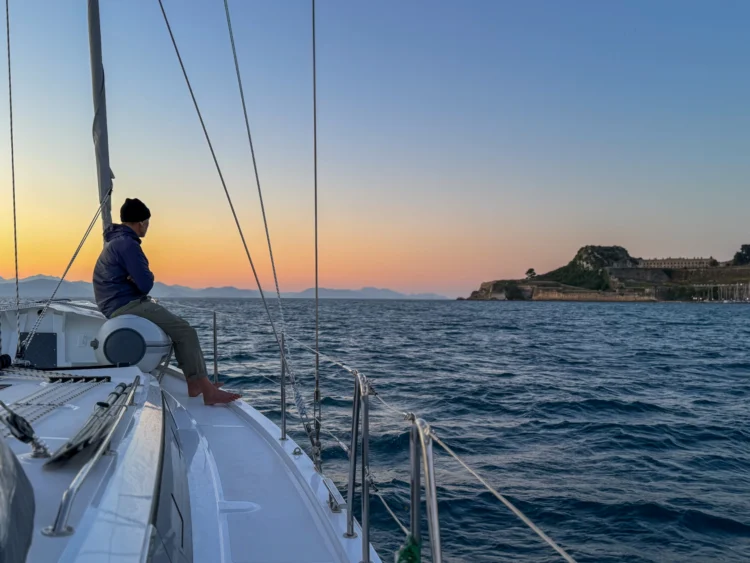 Man looks towards the sun setting behind the sea