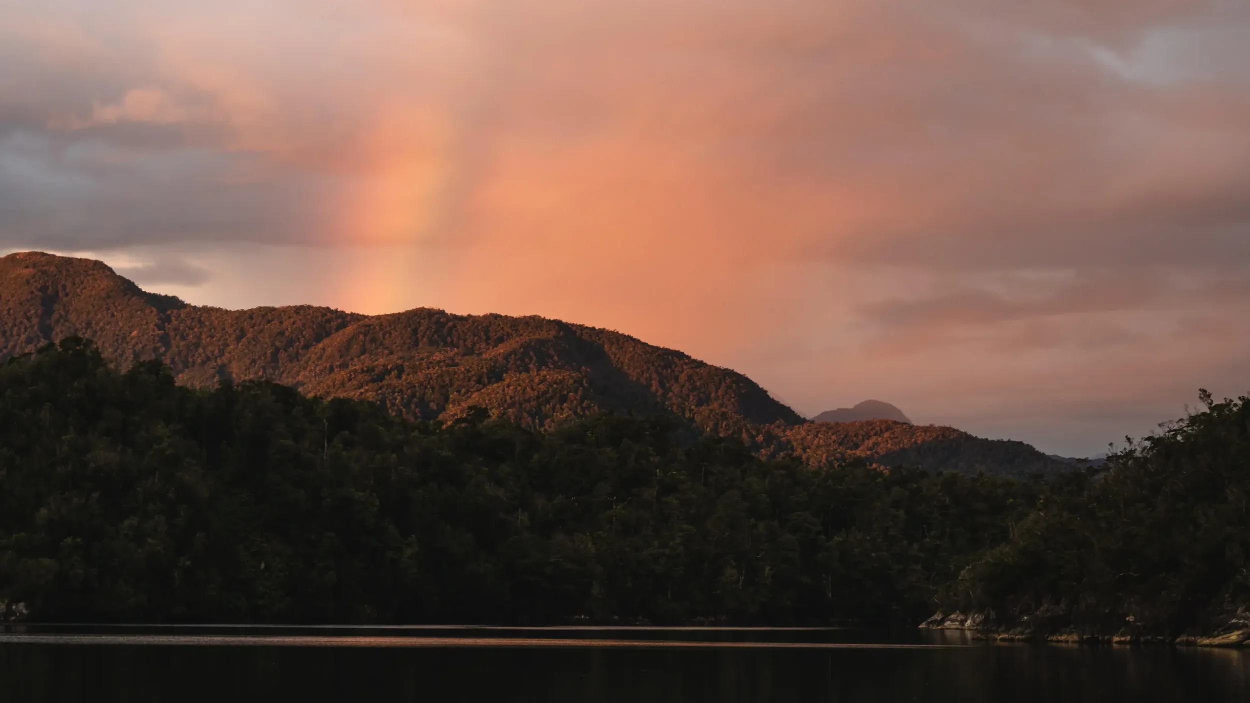 a rainbow over a mountain at sunset
